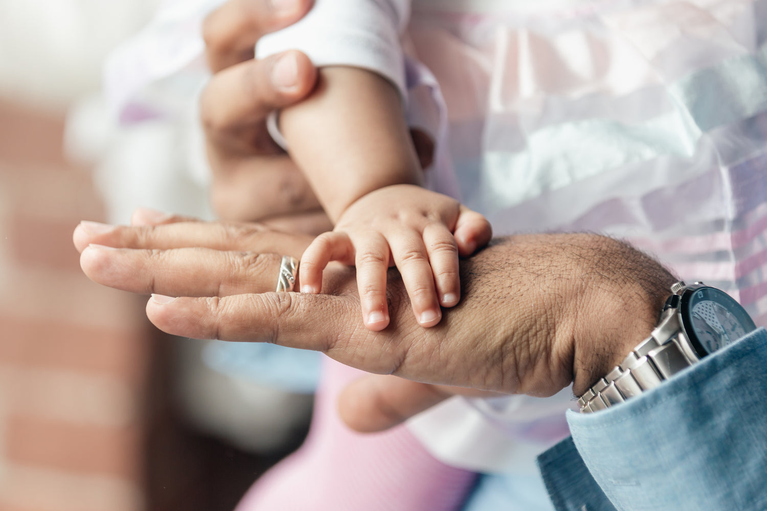 Main d'une petite fille posée tendrement sur celle de son papa, symbolisant un moment de connexion et de douceur entre père et enfant